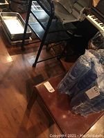 Wooden side table with brown top and visible scratches beside blue wrapped items.