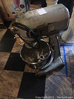 Front and side view of industrial Hobart stand mixer with metal body, stainless steel bowl and beaters inside.