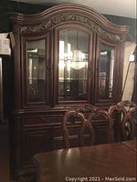 Front view of two-piece dark wood china hutch with ornate crown molding, glass doors, and drawers beneath.