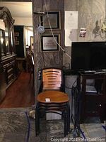 Four wood and metal chairs with horizontal slits in backrests and wooden seats, black metal frames