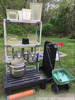 Full lot showing four tier white plastic shelving with plastic containers, mixing bowls, Scotts spreader, sidewalk sign, plastic step stool, and foam roller