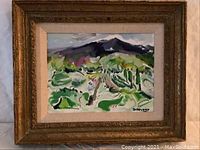 Frontal view of the framed colorful oil on canvas artwork showing a landscape with mountain and meadow composed in vibrant colors.