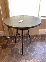 Full view of round slate top table on wrought iron base