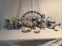 All eight pieces in a row: platter, figurine, pitchers, covered pot, basket dish, vase and trinket box visible