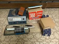 Wide shot showing the directional finder device, nautical accessory boxes, rolls of adhesive tape on marbled surface