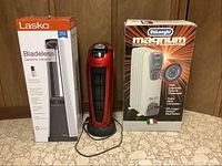 Photo showing the Lasko bladeless ceramic heater in gray with box, red Heat-Wave oscillating ceramic tower heater, and DeLonghi Magnum oil-filled radiator with box.