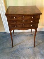 Front view showing three drawers, bird’s eye maple veneer top, mother-of-pearl knobs and brass keyholes