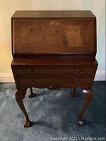 Front view of the small mahogany Georgian style writing desk showing the drop front and two drawers below with carved legs.