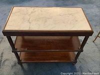 Front view of occasional table showing marble top and two wooden shelves with visible wear.