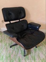 Front and side view showing leather upholstery, button tufts, plywood shell, and metal base