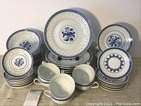 Full set arranged showing plates, bowls, saucers, and teacups in blue and white floral pattern with pierced edges on plates.