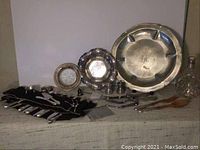 Overview of assorted sterling service pieces including platter, bowl, plates, decanter, shakers and flatware displayed on table