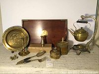 Full lot of mixed brass decorative items including hanging teapot, tray with Chinese character, boxes, small plate, vases, salad servers, candle holder, and finials.