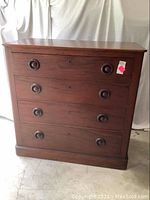 Full front view of antique highboy dresser showing four drawers and wooden knobs.