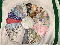 Close-up of one Dresden Plate block on the quilt showing multicolored fabric segments and a white center.