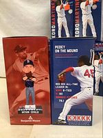 Close-up of two bobblehead boxes: one Nathan Eovaldi and one Pedro Martinez, showing box art and player images.