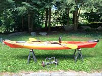 Full side profile of kayak on sawhorses with trolley visible below