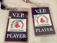 Two laminated VIP Children's Hospital Celebrity Classic player passes with red and blue design and signatures.