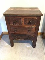 Front view of the primitive style nightstand showing 4 drawers with dark wood and metal ring handles.
