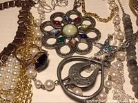 Close-up of mixed costume jewelry focusing on necklaces, pendants, brooches with enamel and synthetic stones.