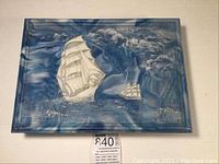 Top view of the rectangular blue and white marbleized jewelry box with relief design of two tall ships on the open sea.