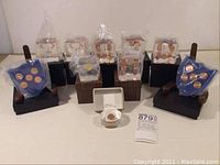 Group shot of ten acrylic paperweights with US pennies and replica gold piece, some in original plastic wrap and boxes, two shield shaped on wooden stands.