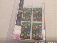 Close-up image of green themed US stamp plate blocks with plate number visible, showing four stamps per block in unopened envelope.