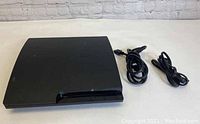 Sony PlayStation 3 console front side view with power and HDMI cables to the side.