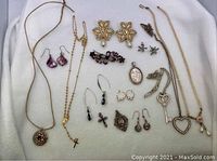 Full lot of assorted sterling silver and costume jewelry including necklaces, earrings, brooches, and pendants arranged on white fabric.