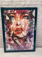 Full view of the framed abstract expressionist wall art showing a colorful face.