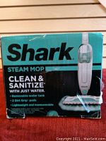 Photo of the Shark Steam Mop box showing product name and main features including clean and sanitize with just water, removable water tank, 2 Dirt Grip pads, lightweight and maneuverable.