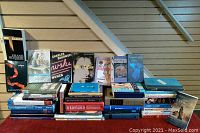 View of assorted stacks of books including novels, reference, and self-help books.