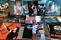 Overview of assorted stacked 12x12 promotional posters featuring various artists and franchises