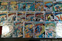 20 vintage Superman comic books laid out in rows on a flat surface, showing colorful cover art and titles including Superman, Superman Family, and other Superman series.