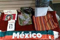 Overview photo showing folded fabrics including red table cloth, animal print bedding, crafting panels, Mexico banner