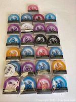 Full lot of 25 E-Circuit earbuds in original packaging, showing various colors and rhinestone accents on cases.