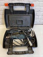 Open black plastic carrying case containing Wizard rotary tool and accessories, shows dirt and wear