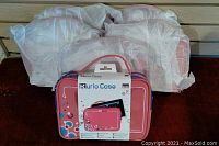 Six pink Kurio tablet travel cases wrapped in plastic, stacked together with one case showing front and packaging visible.