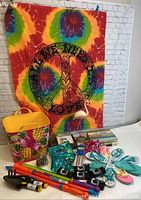Photo showing entire lot including tie-dye tapestry, flamingo statue, pineapple bucket, disposable cameras, garden tools, flip flops, seed packets, and decorative sign