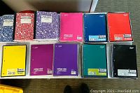 Photo showing assortment of notebooks in various colors including composition and spiral styles.