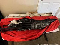 Folded canopy metal frames and accessories inside red carrying bags and original packaging boxes.