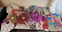 Overview of assorted glittery faux flowers in gold, red, purple, small stickers, white woven baskets, foam bases, gift bags.