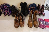 Photo of 7 pairs of ladies boots and 2 pairs of tights displayed on a table, showing various styles including sequin, floral, animal print, and solid colors.