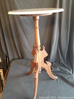 Full view of antique Eastlake side table showing round white marble top and carved wooden base with three legs and central column.