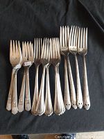 Photo showing three different silverplate dinner fork designs laid out on a black cloth.