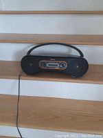 Front view of the Sony portable CD and radio player showing the full device on wooden stairs, illustrating the overall condition and size.