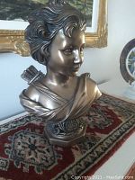 Front and side views of the bronze-tone bust statue showing detailed facial features, draped garment, and quiver with arrows on back.