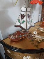Front view of the stained glass tulip design lampshade mounted on handpainted Dutch wooden clog base on a decorative surface, showing overall appearance and color.