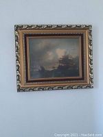 Full view of the framed painting showing the ornate gold frame and the dark stormy sea with ships.