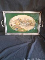 Front view of rectangular antique metal tray with green background and colorful oval illustration of horse carriage and rural scene.